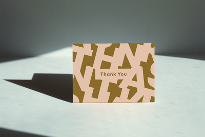 Thank you greeting card thank reads "thank you" and has the letter's of "Thank you" in the background'