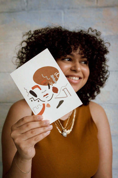 smiling woman holding abstract illustration card with neutral color tones
