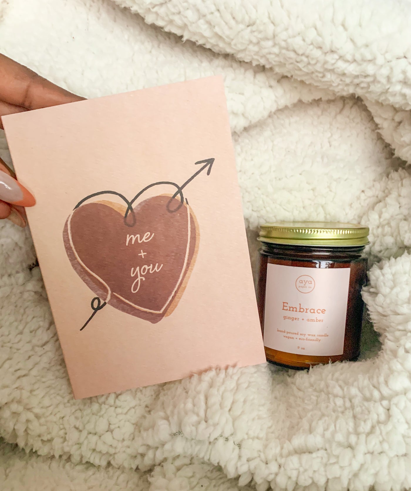 beige and pink colored "Me & You Romance Card" with a heart illustration and within the heart the text reads "Me + You" showcased next to an aya paper candle