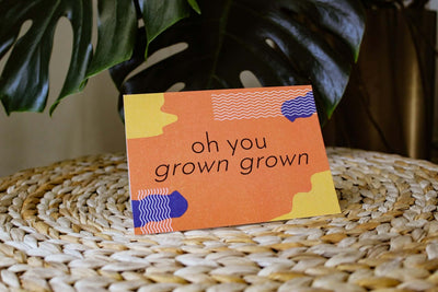 orange "Grown Grown birthday card" that reads "oh you grown grown" in black text with yellow and blue abstract designs