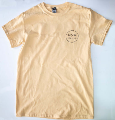 front of the tan colored "Paper Chasers T-Shirt" that has the Aya Paper Co. logo on the chest